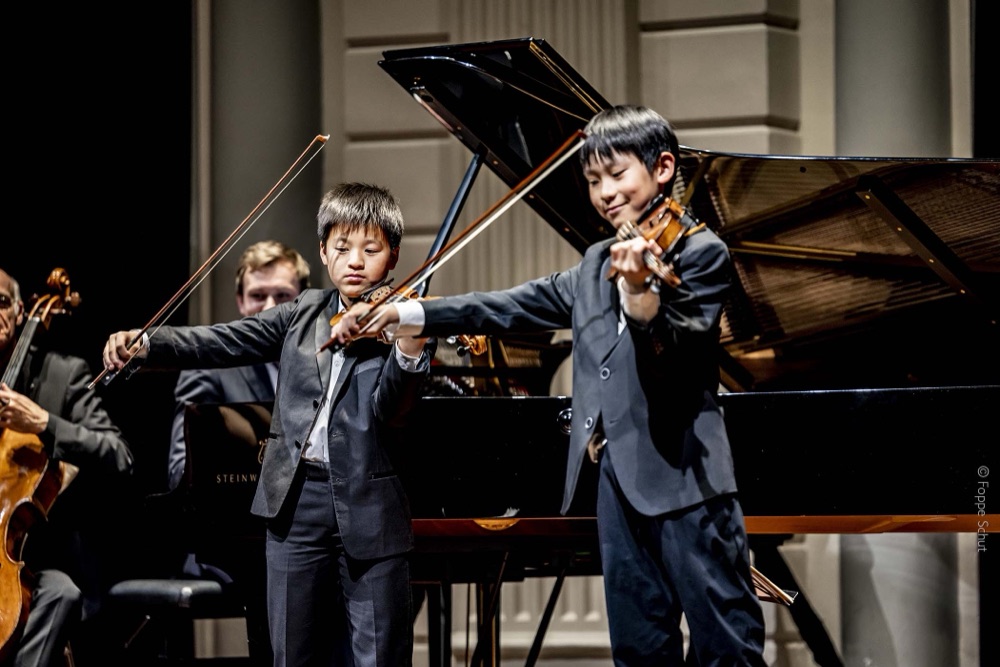 Two young violinists taking a bow after a duo performance